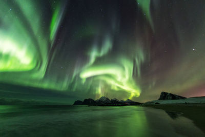 Scenic view of sea against aurora borealis at night