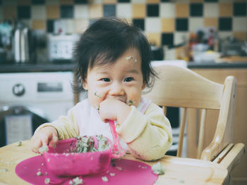 Portrait of cute girl eating food at home