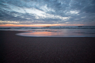 Scenic view of sea against dramatic sky during sunset