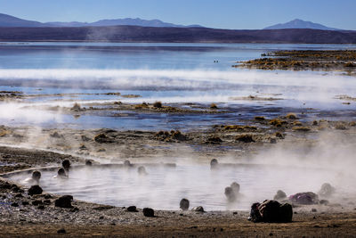 Steam emitting from geysers against sky