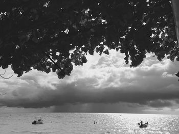 Boats in sea against cloudy sky