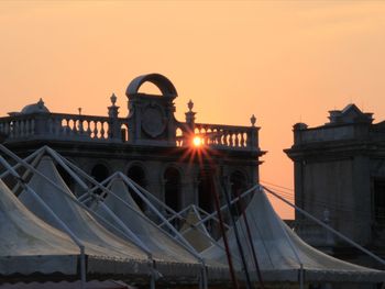 Bridge over buildings against sky during sunset