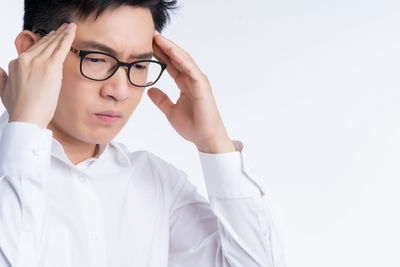 Portrait of young man wearing eyeglasses against white background