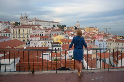 Rear view of woman standing by railing against cityscape