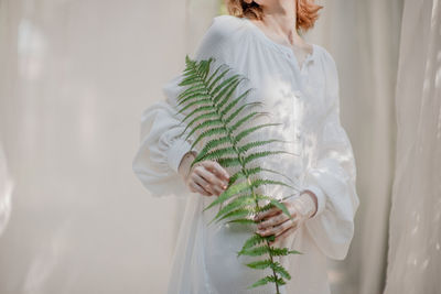 Rear view of woman standing by white wall