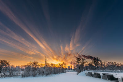 Snow covered field against sky during sunset