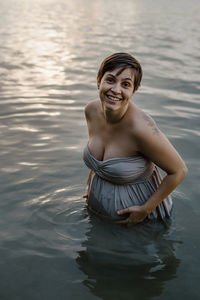 Portrait of a smiling young woman standing in lake