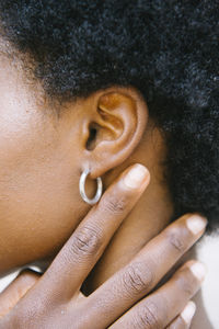 Cropped side view of close up unrecognizable young black woman ear and hand