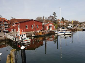 Boats moored at harbor against sky