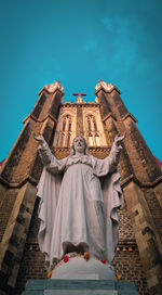 Low angle view of statue against temple building against sky