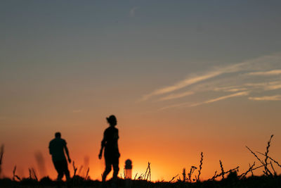 Silhouette people against orange sky