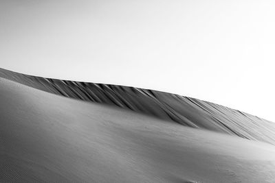 Low angle view of sand dunes against clear sky. showing the texture of sand