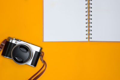High angle view of camera on table against yellow wall
