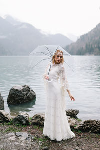 A tender sensual young woman bride in a fashionable wedding dress is standing in the rain in nature