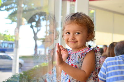 Portrait of cute girl standing by glass wall