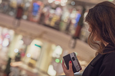 Mid adult woman standing with camera in mall