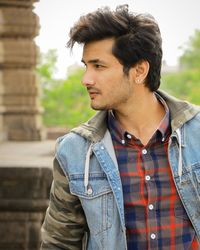 Young man looking away while standing outdoors