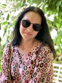Portrait of young woman wearing sunglasses and beige polka dot abstract pattern dress. 
