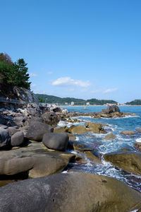 Rocks on beach against clear blue sky
