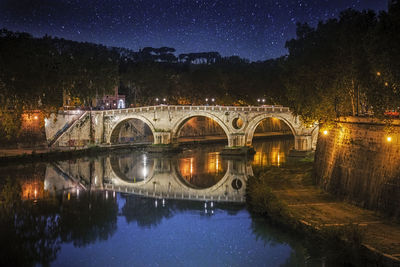 Arch bridge over canal against sky at night