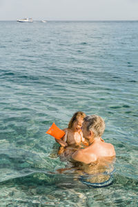 High angle view of father and granddaughter swimming in sea