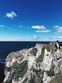 Scenic view of rocks by sea against blue sky