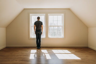 Man stands in front of interior window in empty lonely minimalist room