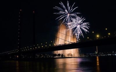 Low angle view of firework display over river at night
