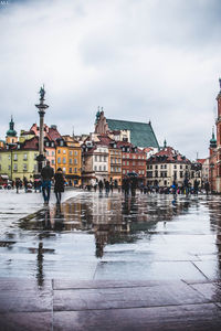 Crowd walking on wet street in city