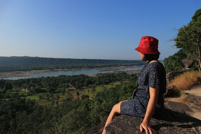 Woman traveler sits and looks at the edge of the cliff.