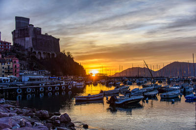 Sailboats moored at harbor against sky during sunset