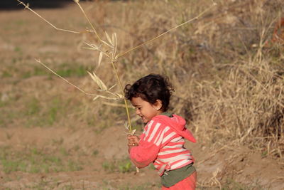 A beautiful indian little child playing in the field holding wood in his hand, india