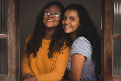 Portrait of smiling sisters by window