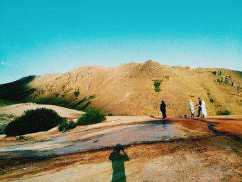 Tourists on mountain against cloudy sky