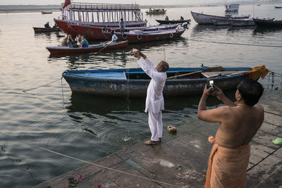 Rear view of men standing on boat in sea