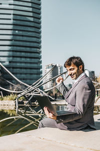 Businessman working on laptop while sitting on promenade