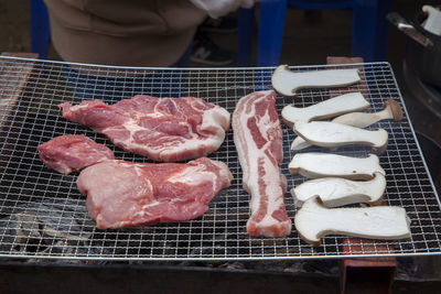 High angle view of mushrooms and pork on barbecue grill