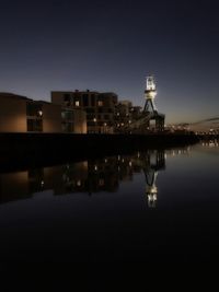 Reflection of illuminated buildings in lake against sky at night