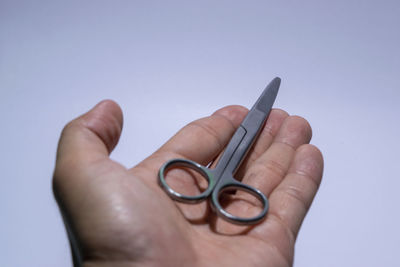 Close-up of hand holding eyeglasses against white background