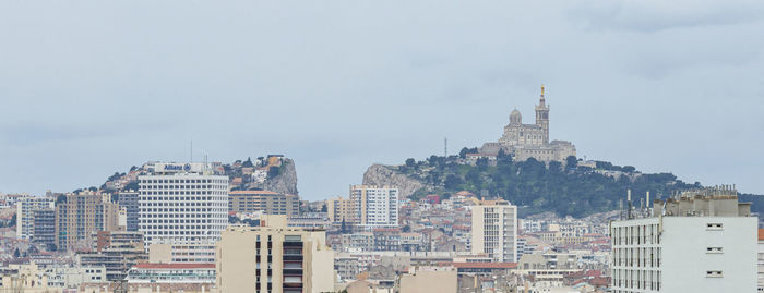 Buildings in city against cloudy sky