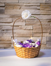 Close-up of purple fabric in wicket basket on table against wall