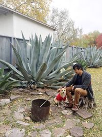 Man sitting on plant against trees