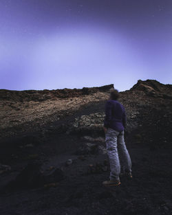 Rear view of man standing on mountain against clear sky