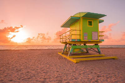 Lifeguard hut on beach against sky during sunset