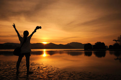 Silhouette of people in lake at sunset
