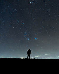 Silhouette man standing on field against sky at night