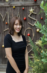 Portrait of young woman standing against plants