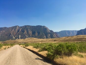 Road by mountains against clear sky