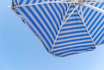 Low angle view of beach umbrella against clear blue sky