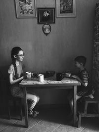 Young woman sitting on table at home